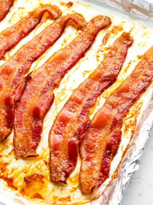slices of cooked bacon on a foil-lined baking sheet.