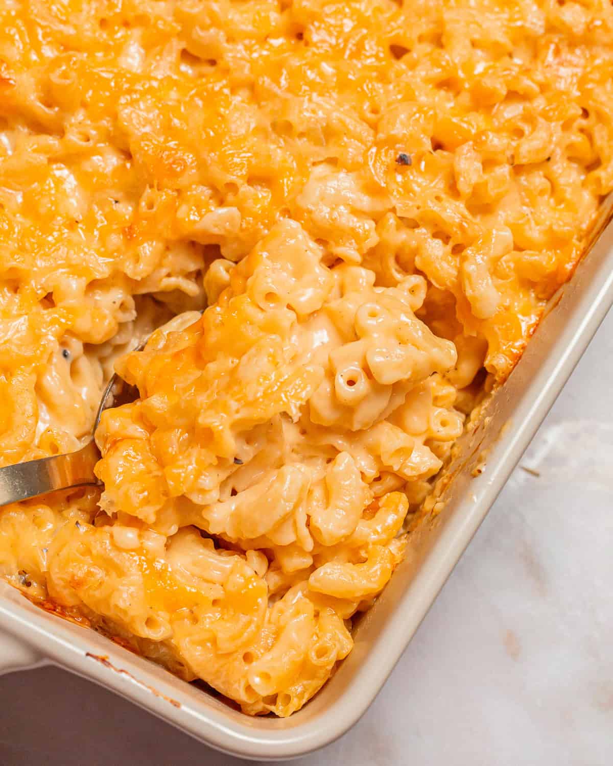 a spoon scooping chick fil a mac and cheese from a casserole dish.