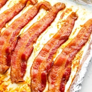 slices of cooked bacon on a foil-lined baking sheet.
