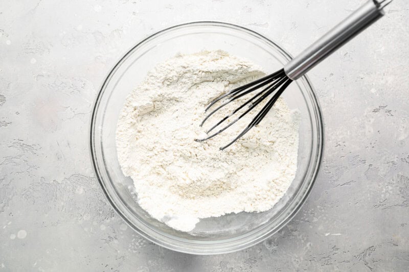 flour in a glass bowl with a whisk.
