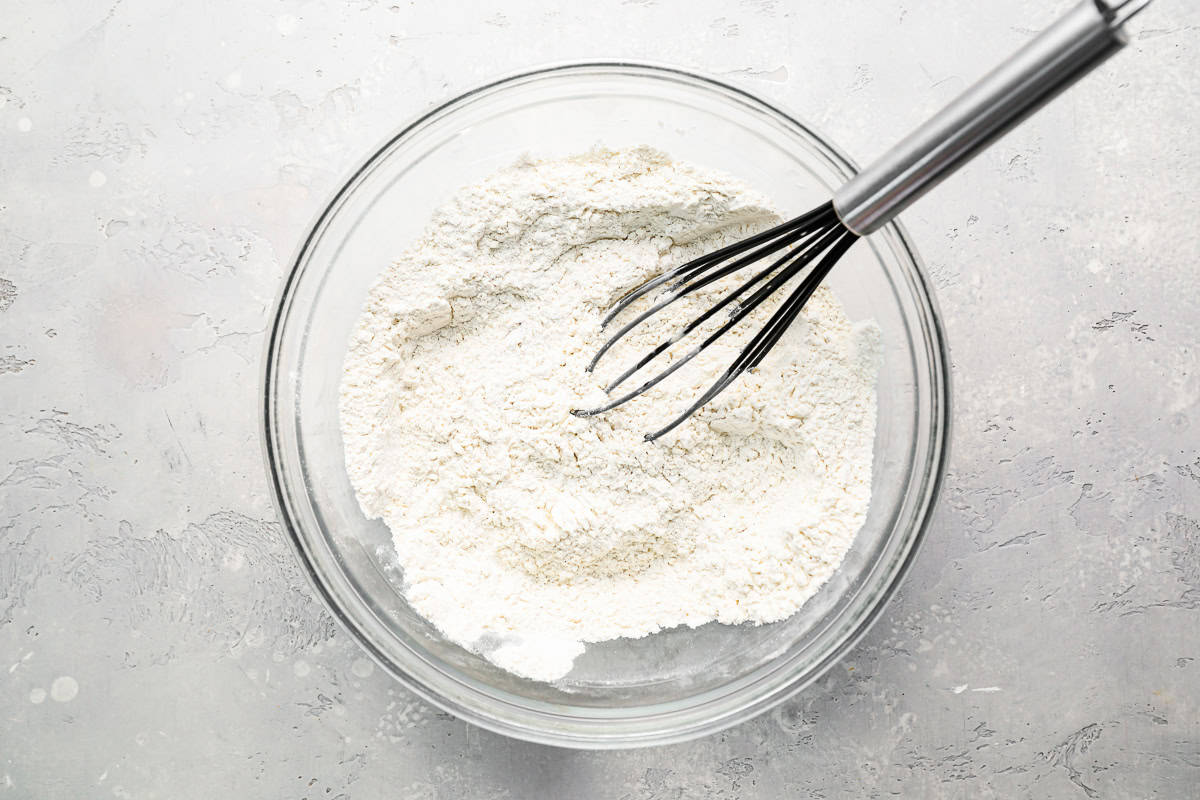 flour in a glass bowl with a whisk.