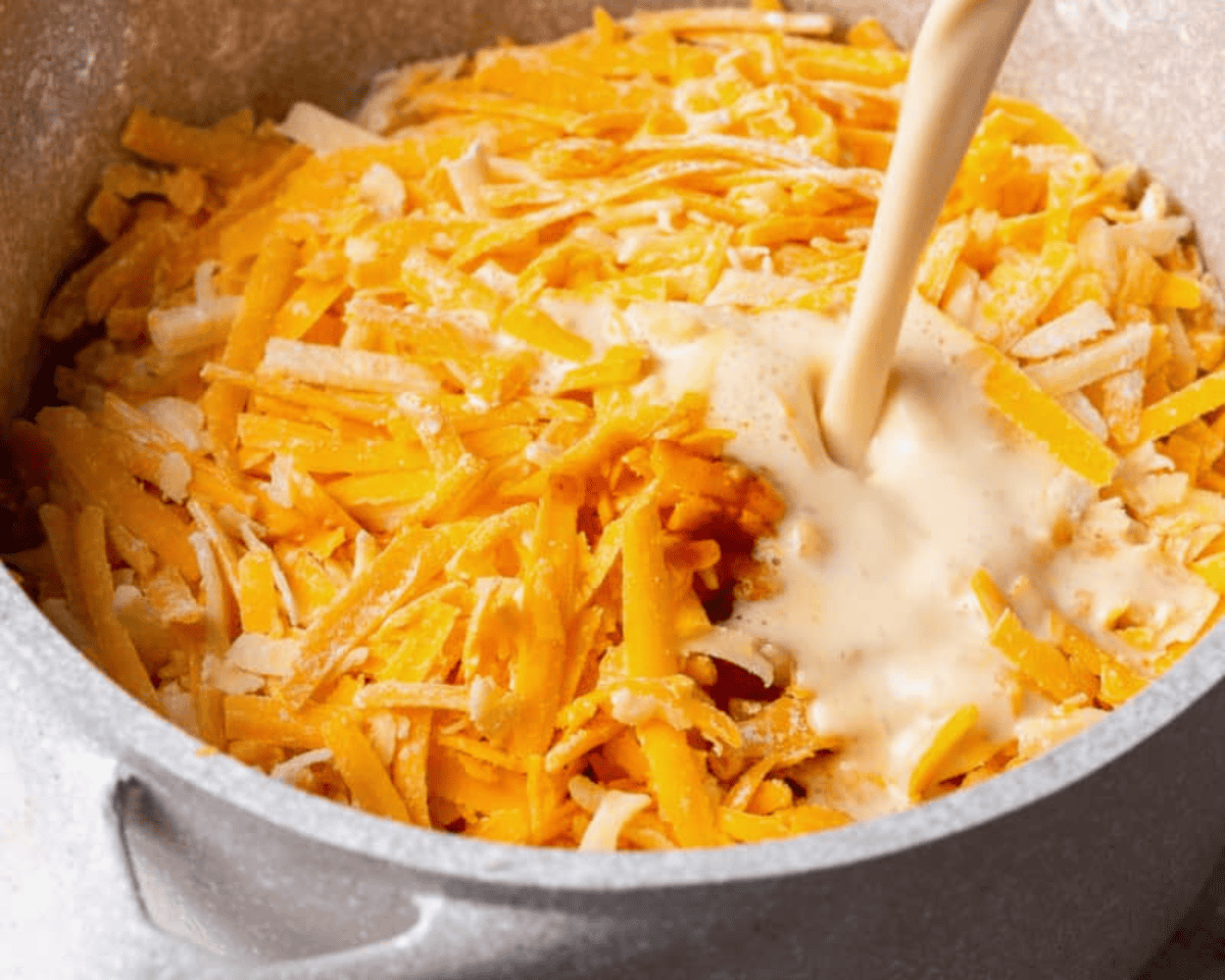 pouring cream into a pot of shredded cheese