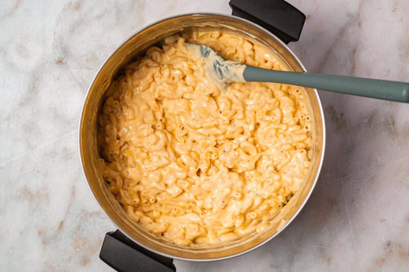 chick fil a mac and cheese in a dutch oven with a rubber spatula.