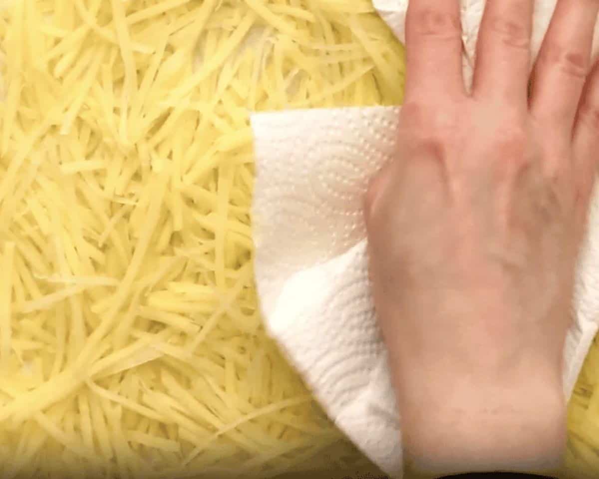 Patting the potatoes dry with a paper towel.