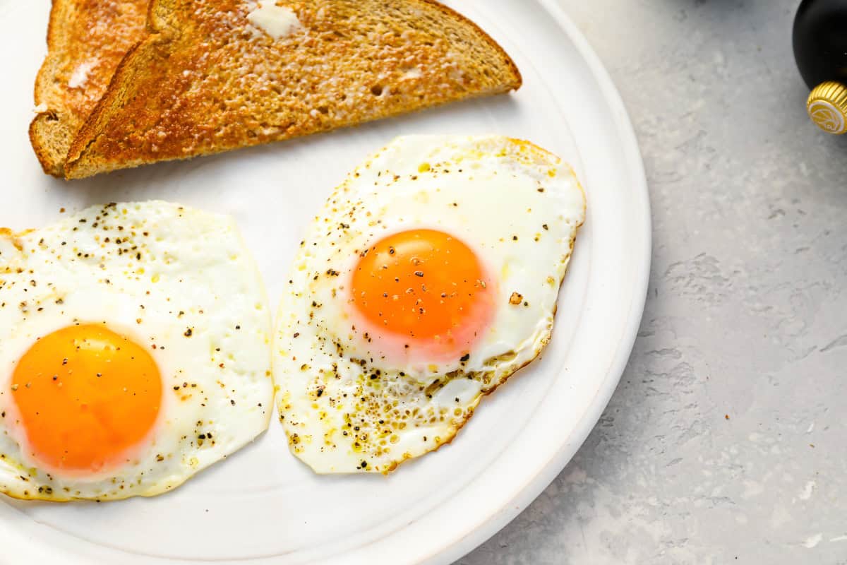 2 sunny side up eggs on a white plate with toast.