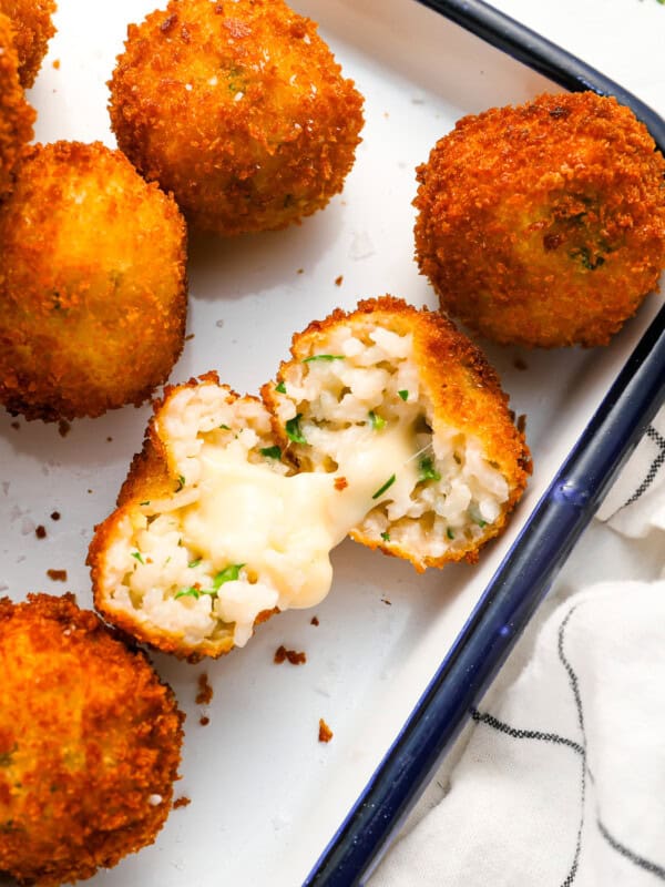 a halved arancini showing its gooey cheese center.