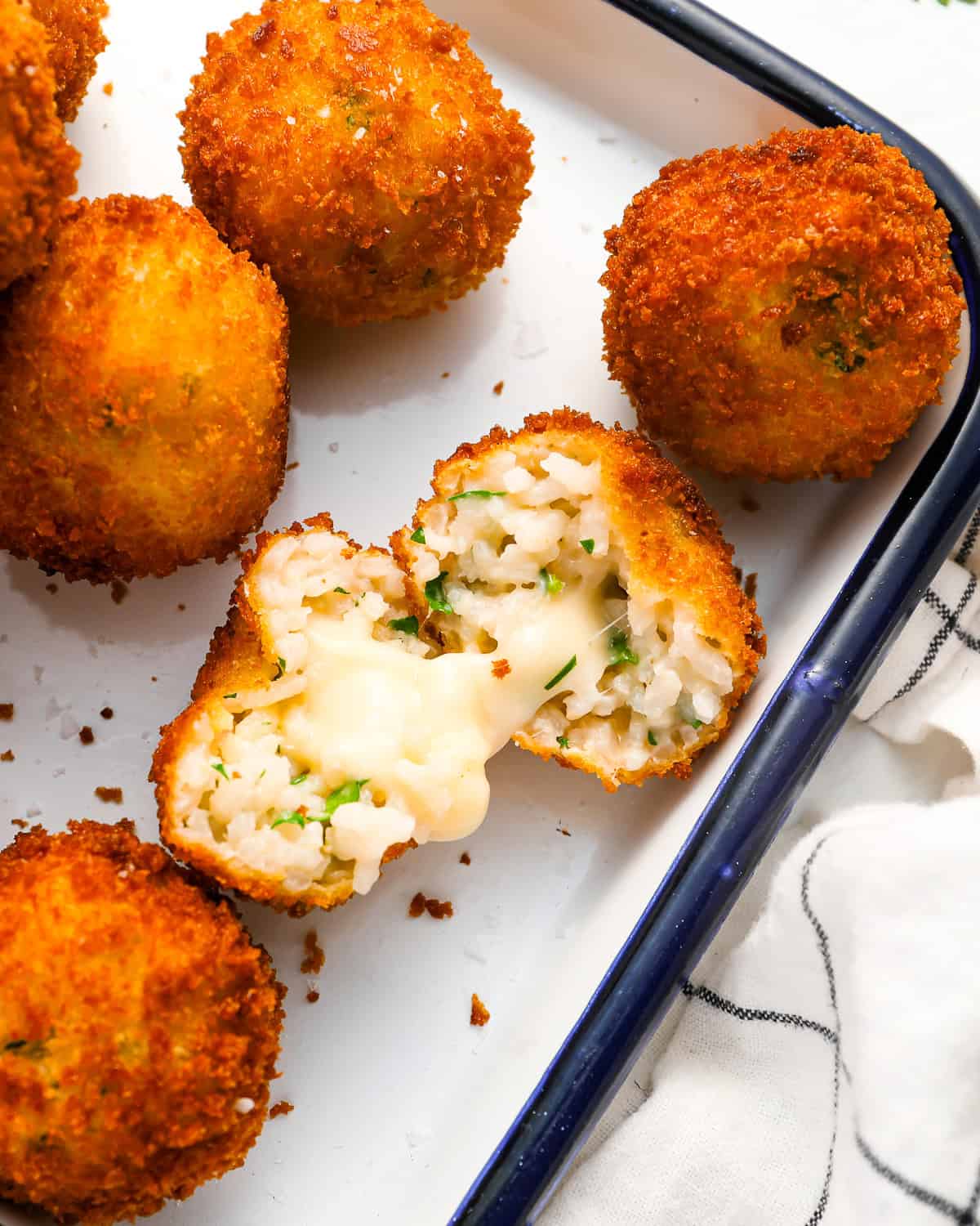a halved arancini showing its gooey cheese center.
