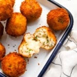 a halved arancini showing its gooey cheese center.