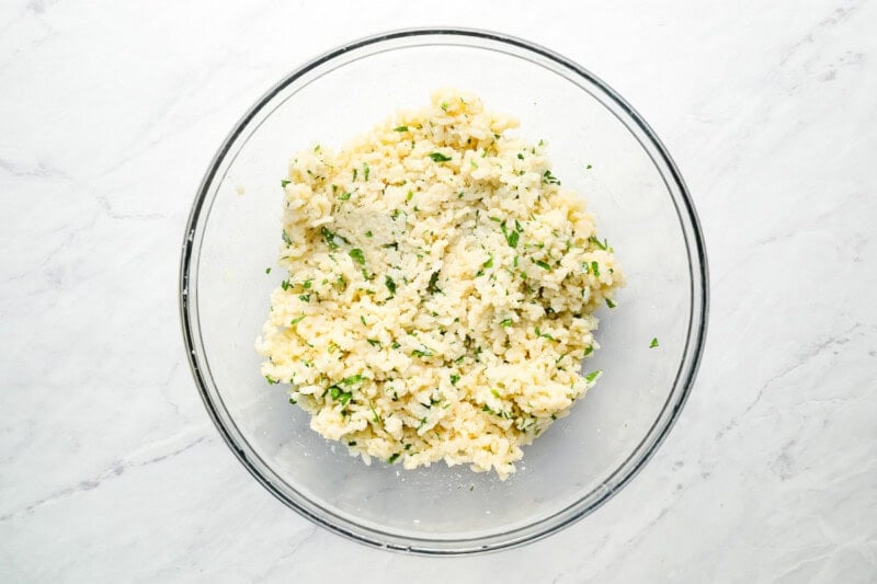 rice mixed with cheese and parsley in a glass bowl.