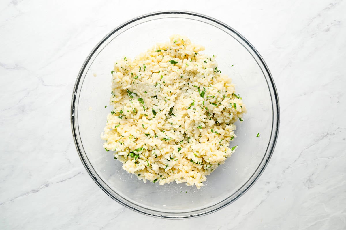 rice mixed with cheese and parsley in a glass bowl.