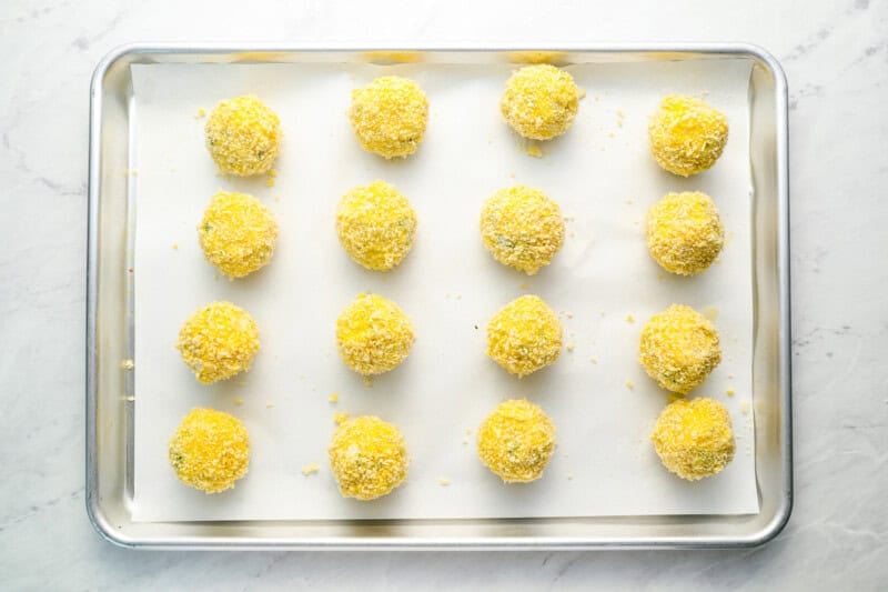 breaded arancini on a baking sheet.