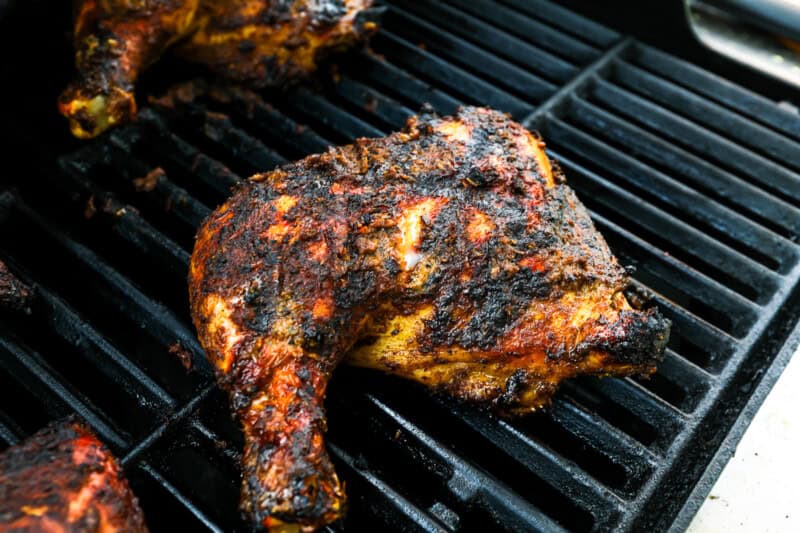 grilled jerk chicken leg quarters on a grill.