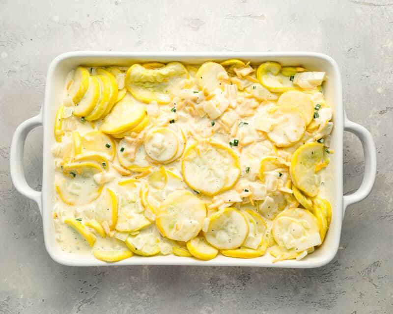 cooked yellow squash mixed with sour cream, eggs, and mayo in a baking dish.