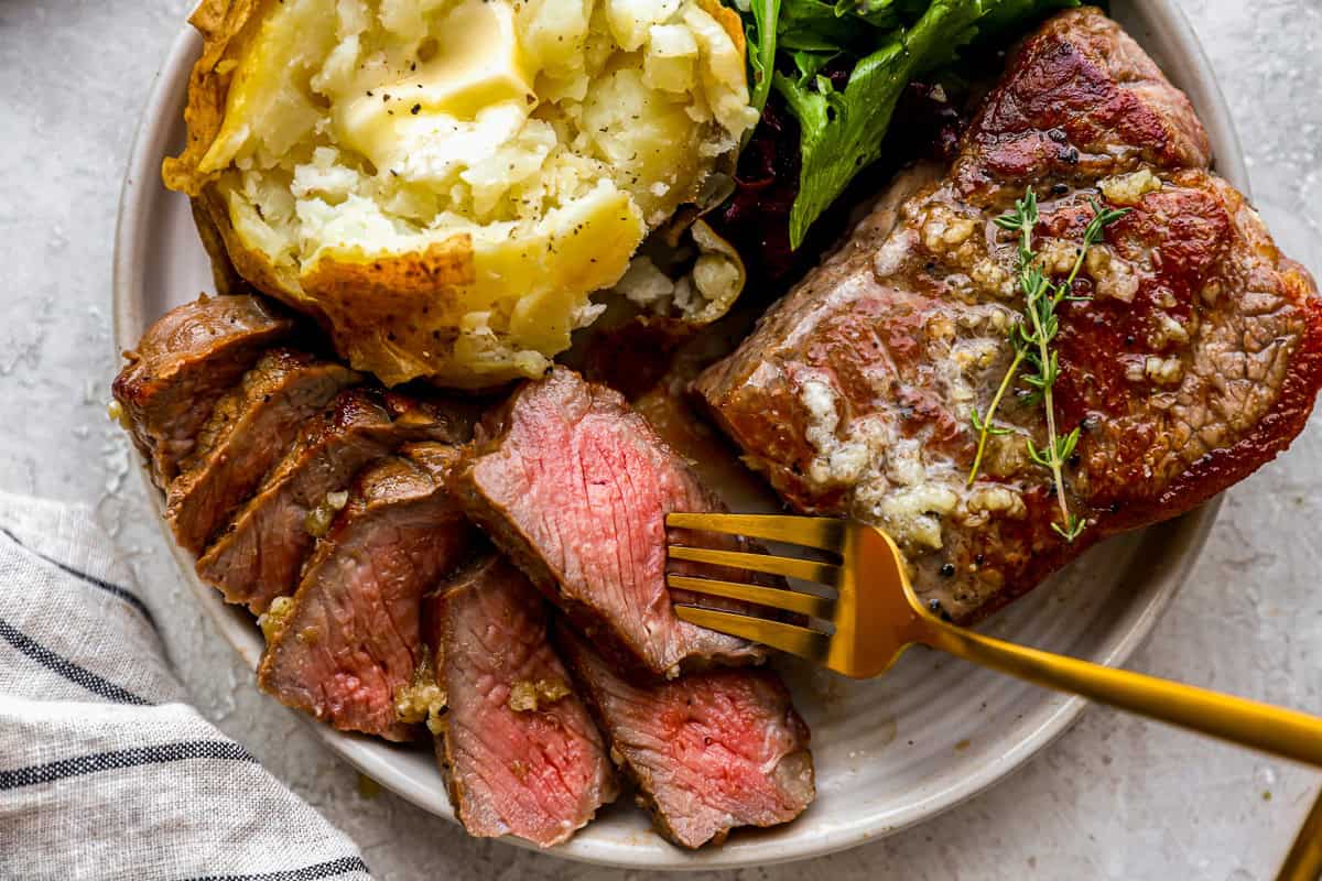 a plate of steak and baked potato