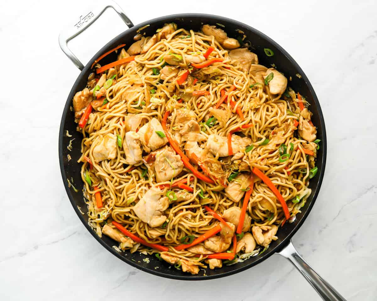 stir fry noodles with chicken and veggies in a black skillet