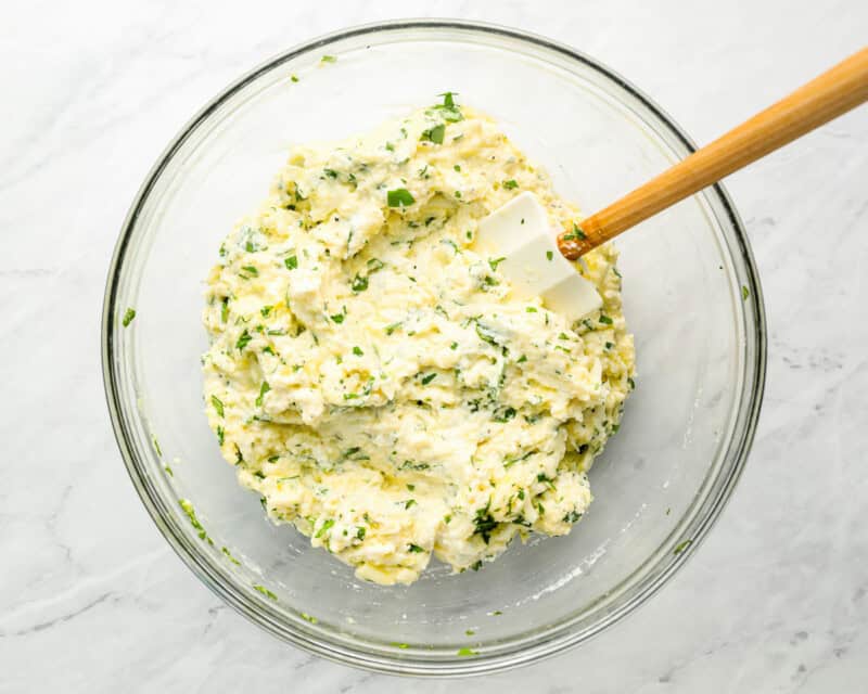 ricotta and herbs in glass bowl with wooden spoon
