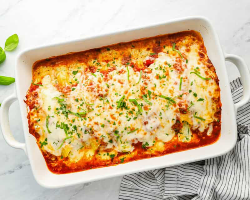 baked manicotti with belted cheese and herbs in white baking dish