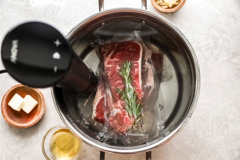 2 vacuum packed new york steak strips submerged in water with sous vide machine