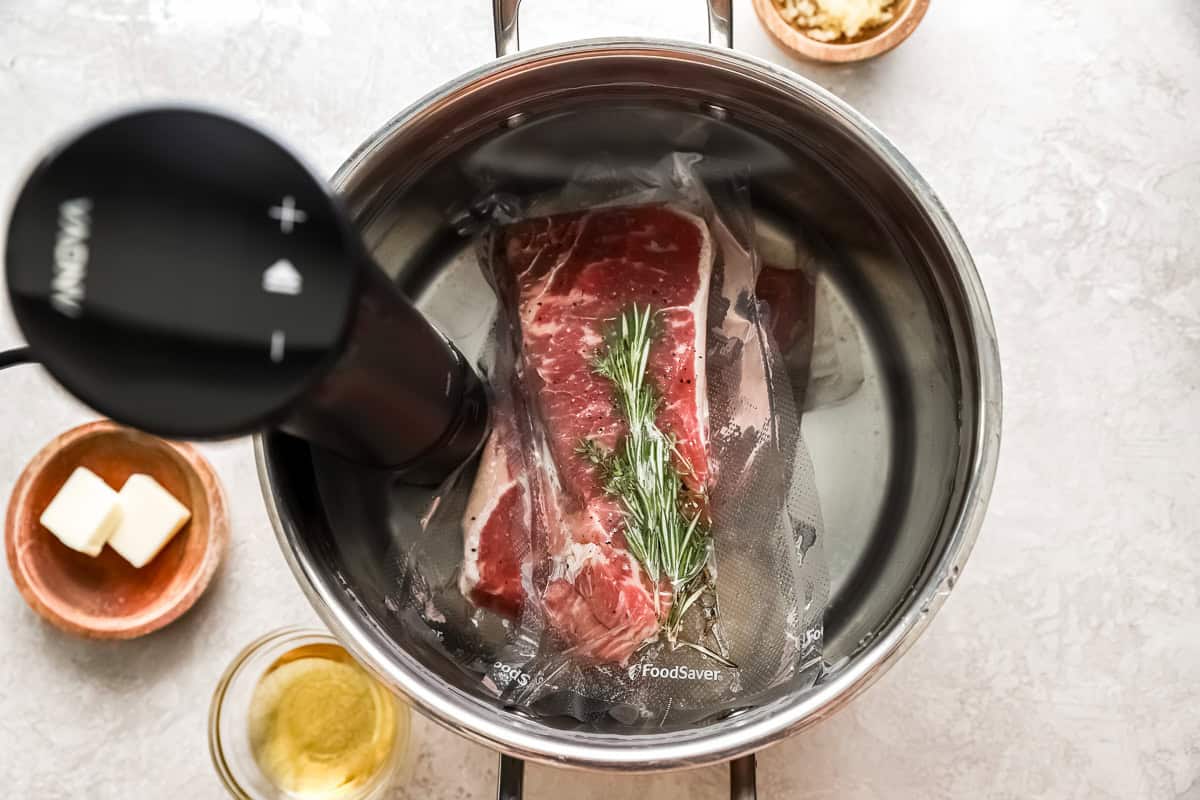 2 vacuum packed new york steak strips submerged in water with sous vide machine