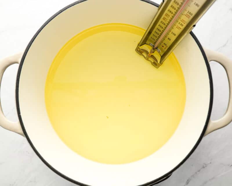 A pot of oil heating on the stove with a thermometer inserted, indicating preparation for frying sopapillas.