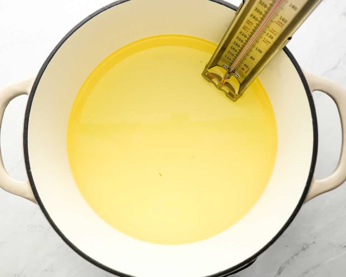 A pot of oil heating on the stove with a thermometer inserted, indicating preparation for frying sopapillas.