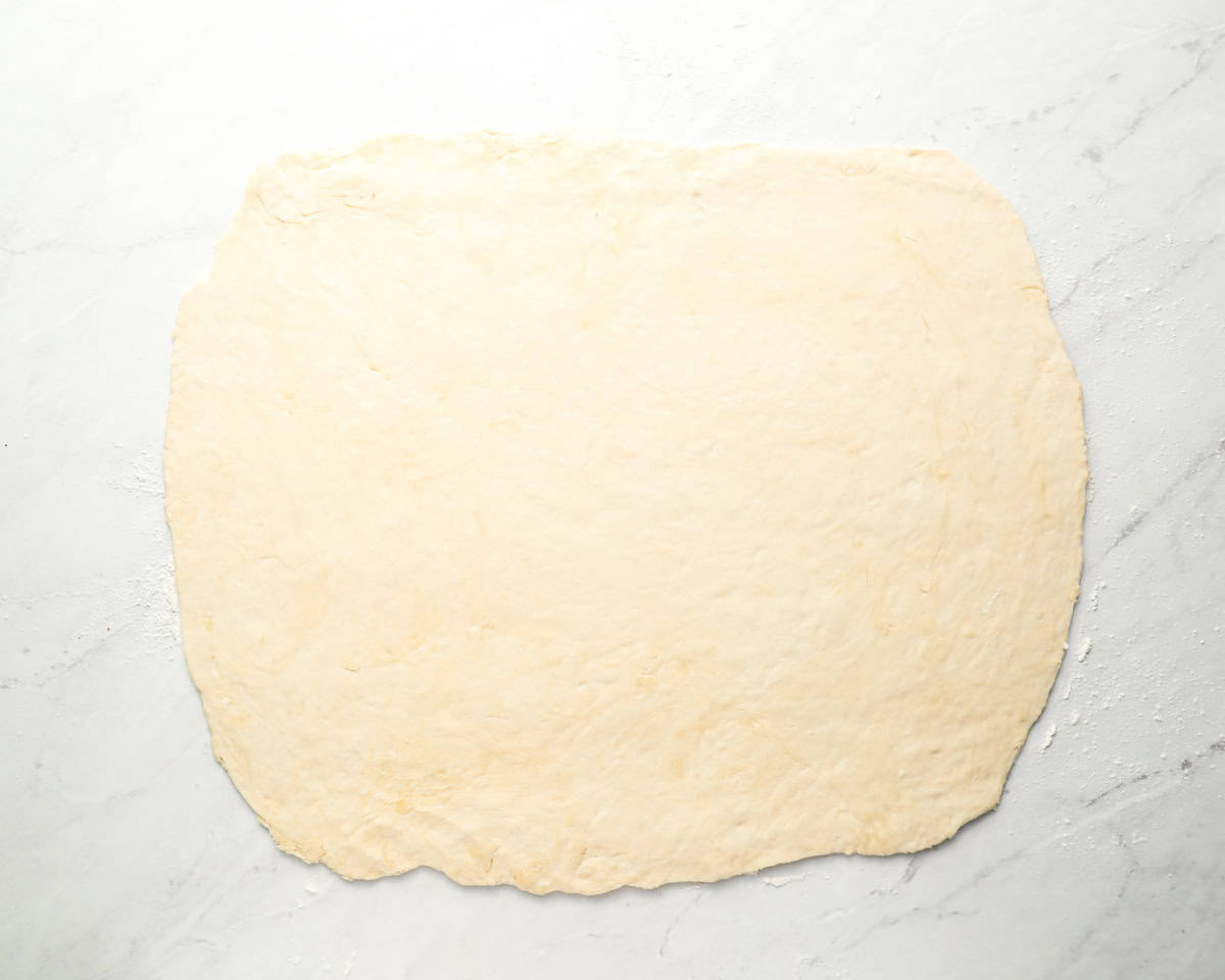 Rolled-out sopapilla dough on a floured surface, ready to be cut.