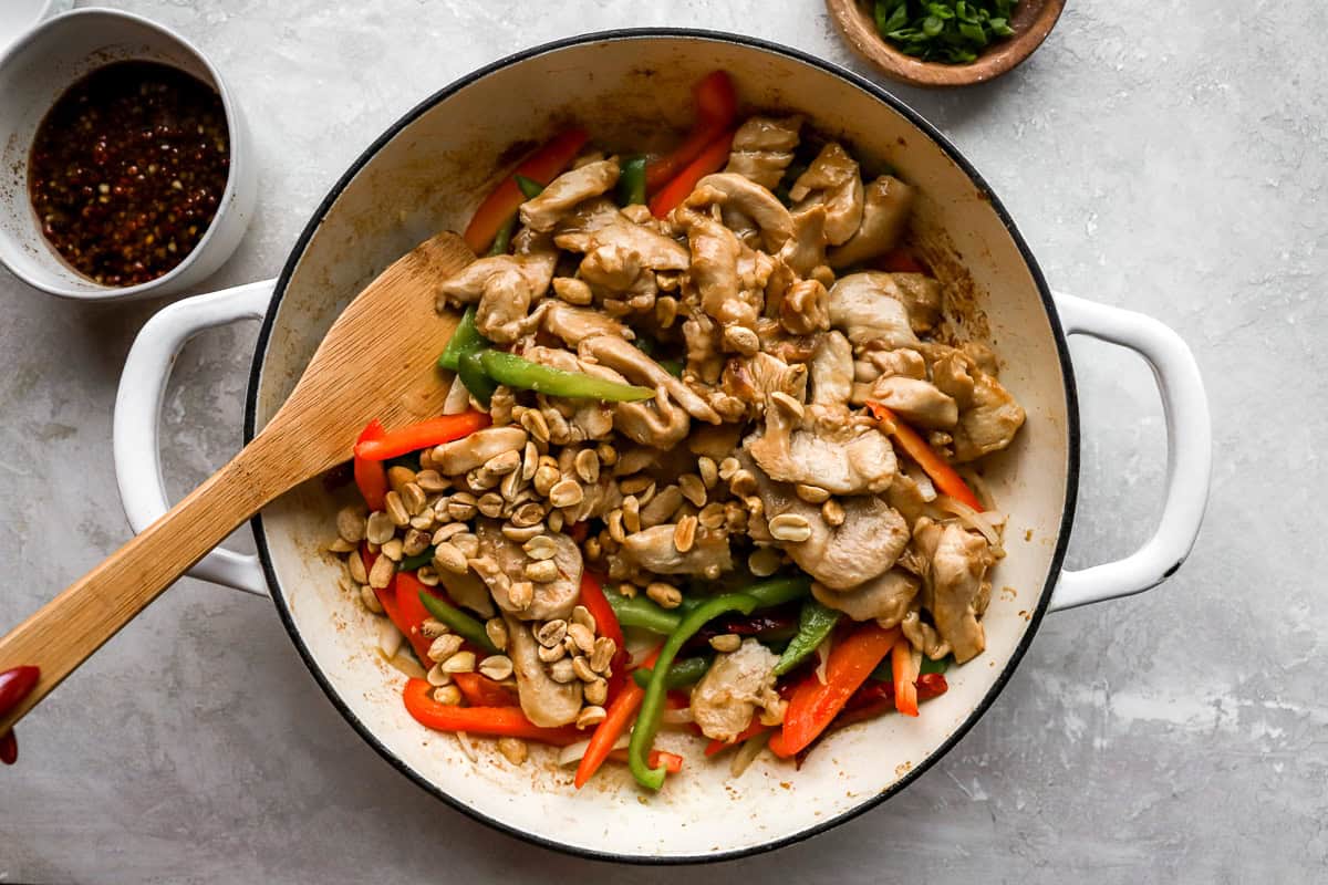 Cooked chicken, vegetables, and peanuts mixed together in a skillet, showing a vibrant Szechuan chicken dish.