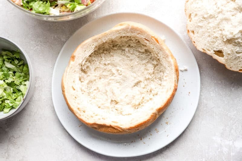 A round loaf of Italian bread with the center removed, creating a space to fill with hoagie dip.