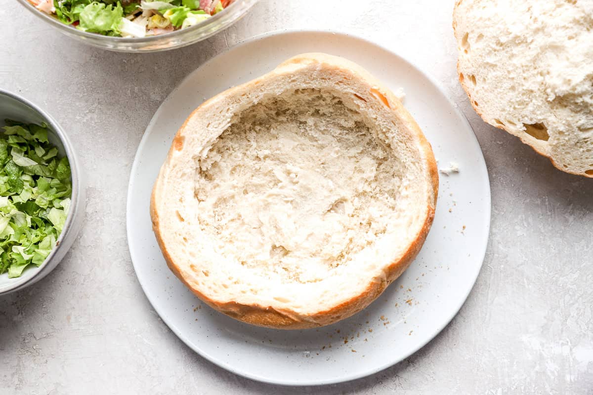 A round loaf of Italian bread with the center removed, creating a space to fill with hoagie dip.