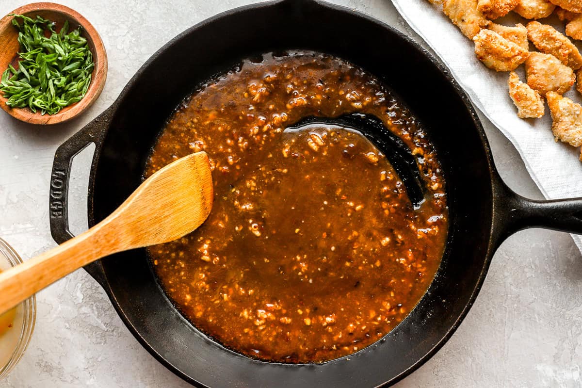 Thickened sweet and spicy General Tso’s sauce bubbling in a black cast iron skillet, ready to coat the chicken.