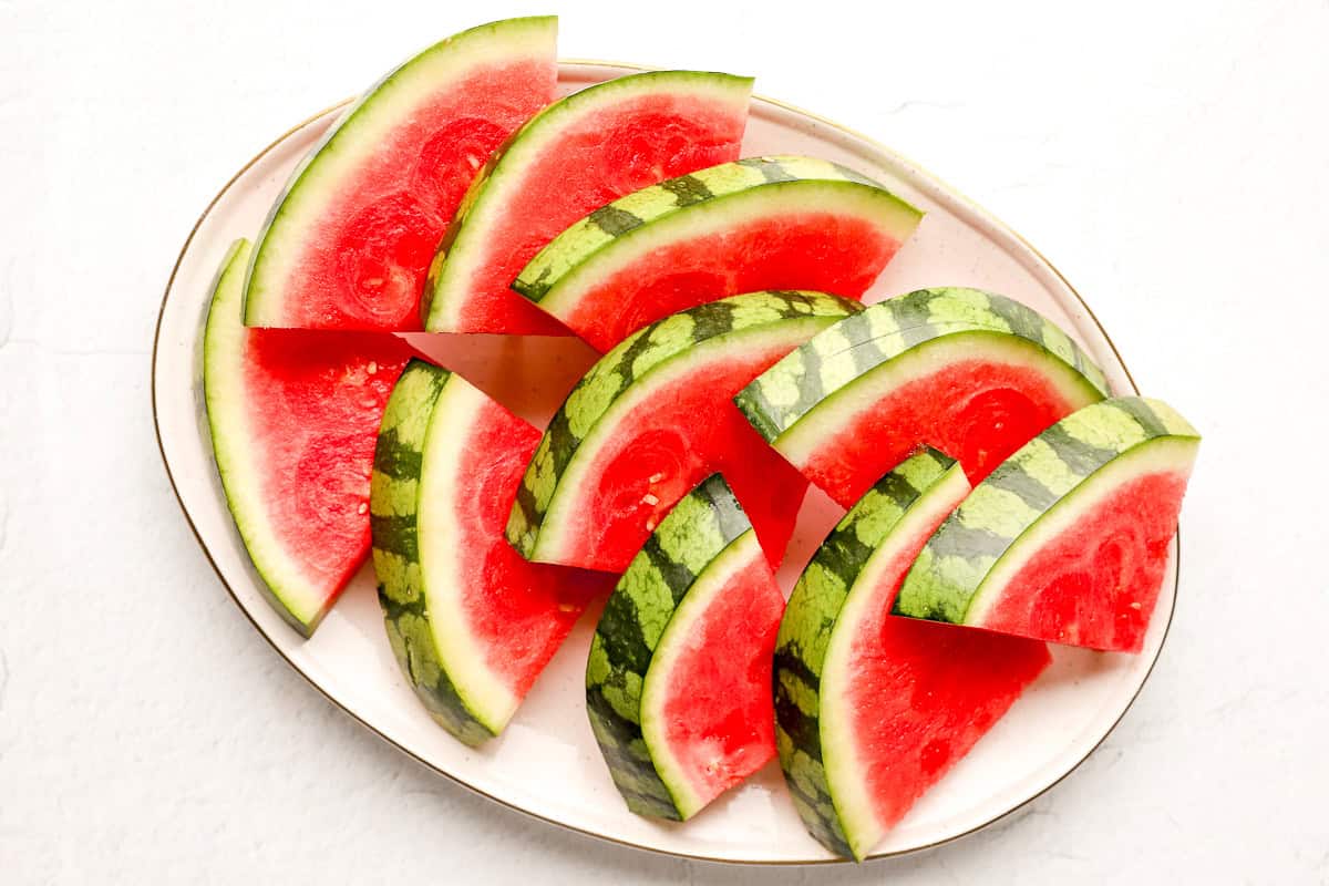 Finished watermelon triangle slices arranged neatly on a white oval serving plate, ready to serve.