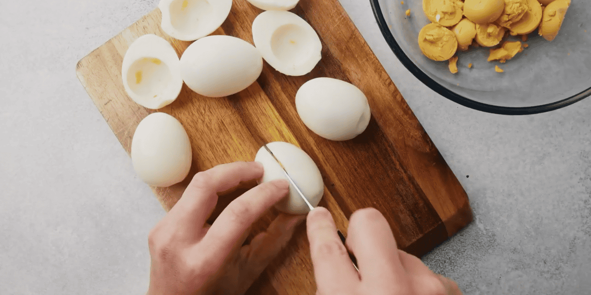 cutting eggs in half and transferring yolks to a bowl
