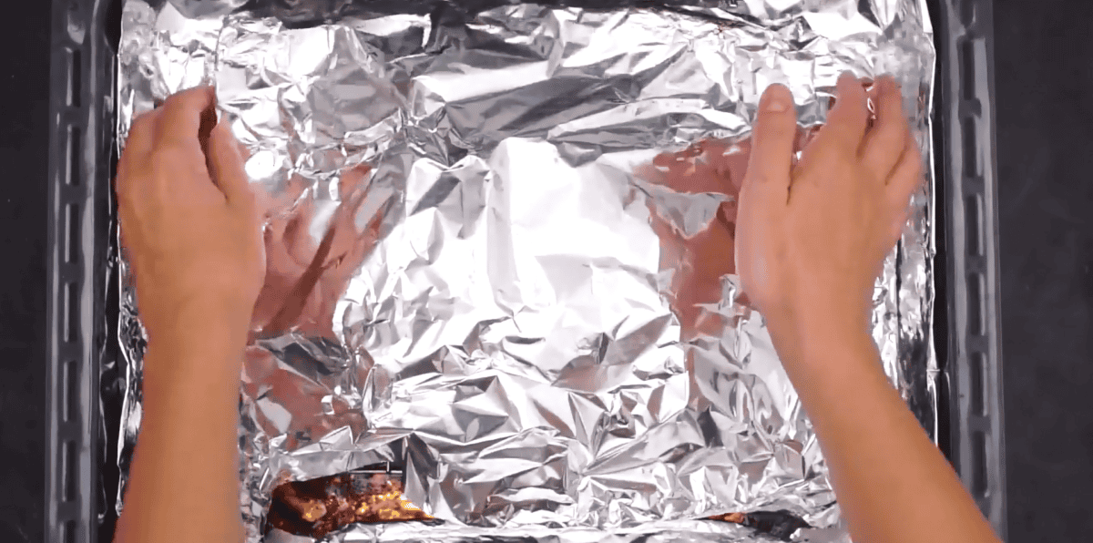 ribs covered with aluminum foil resting.
