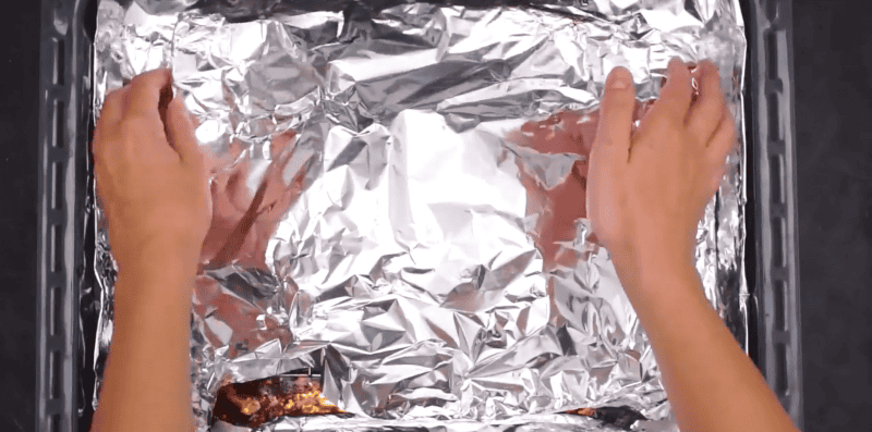 ribs covered with aluminum foil resting.