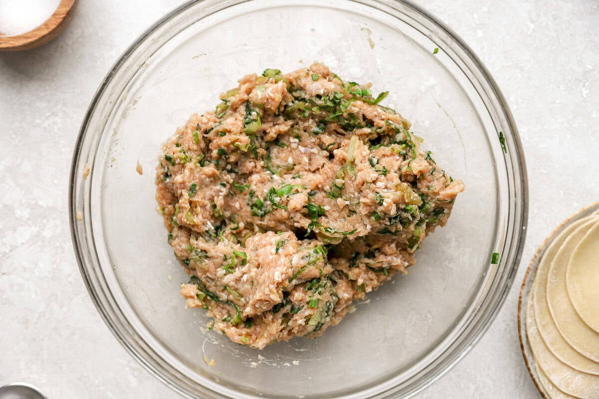 The potsticker filling mixed together in a glass bowl—ground chicken blended with sautéed cabbage and green onions.