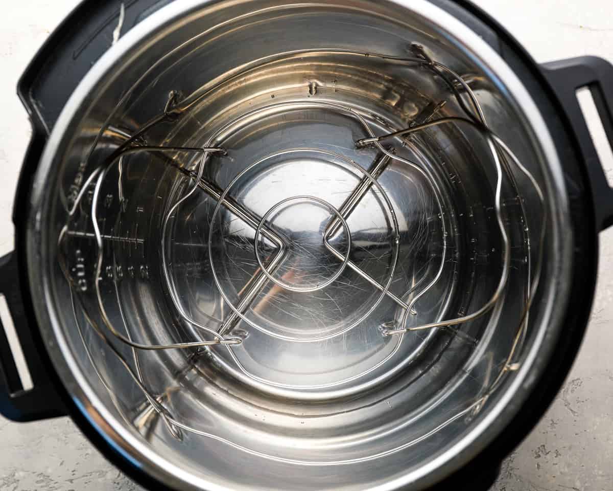 An empty Instant Pot with the metal wire rack/trivet positioned at the bottom, ready for use.
