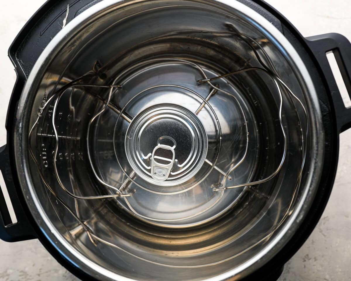 An unopened can of condensed milk placed on the rack inside an Instant Pot, ready to be cooked.