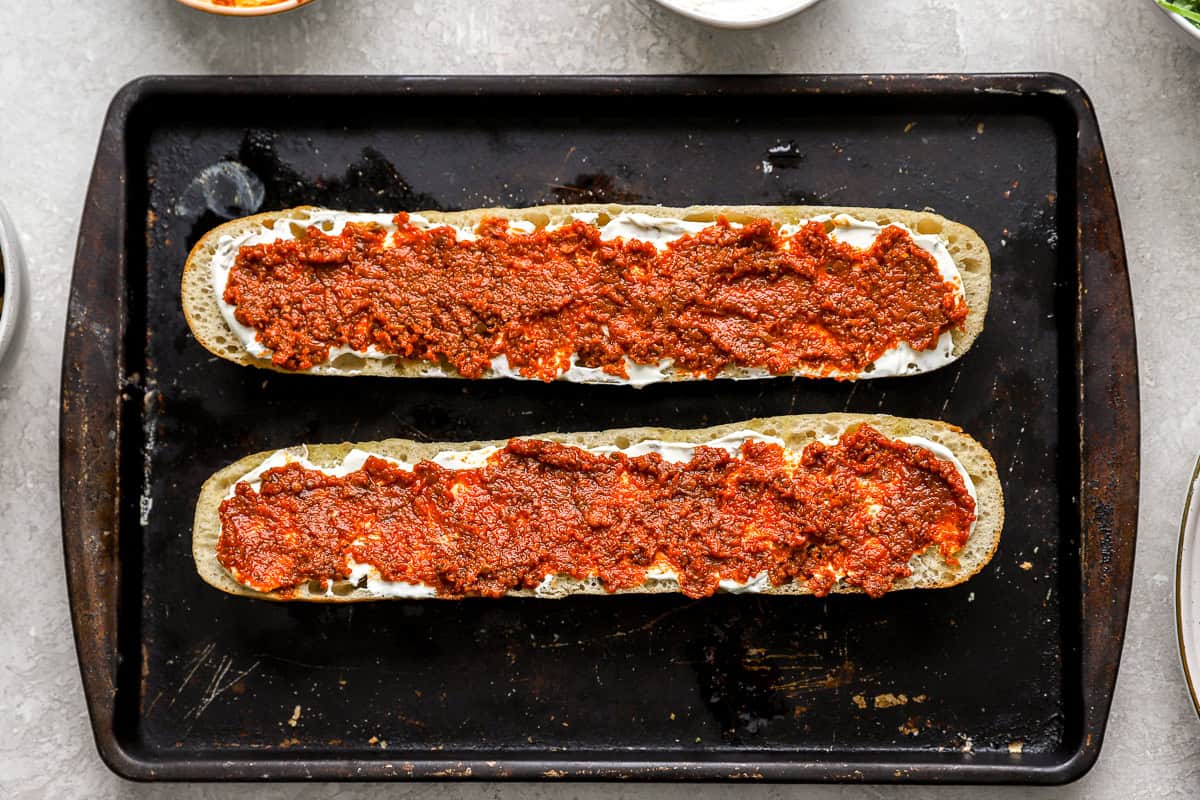 Toasted baguette halves layered with garlic herb cream cheese and a generous amount of roasted red pepper spread.