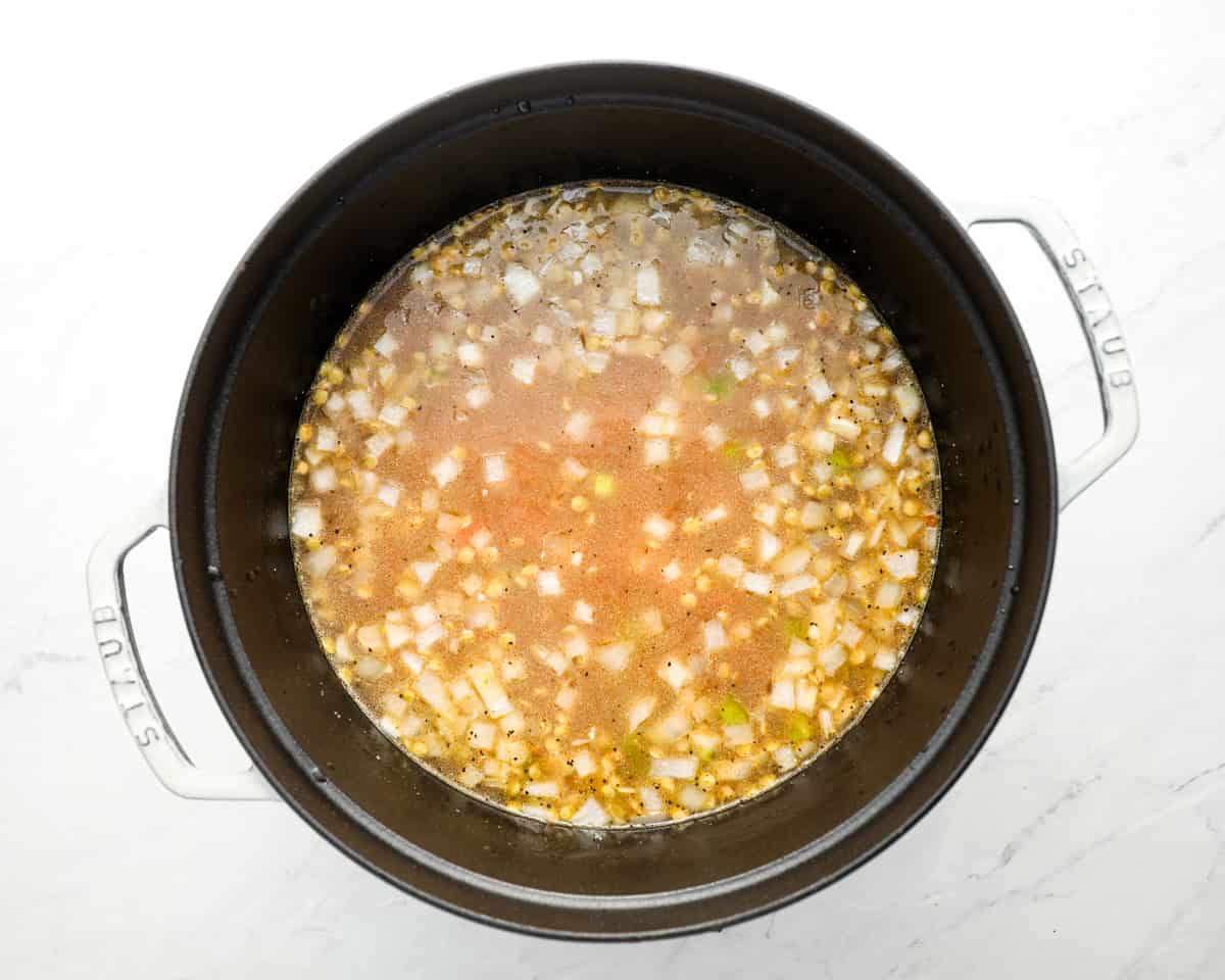 Broth added to the sautéed vegetables in the Dutch oven, with lentils just beginning to cook.