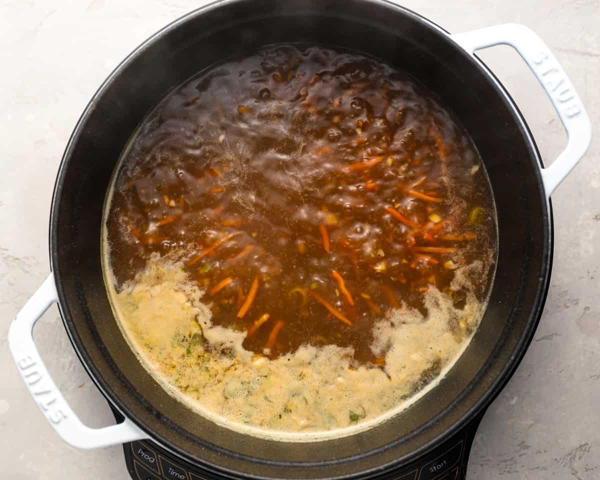 The soup at a boil with visible shredded carrots and miso foam rising to the top.