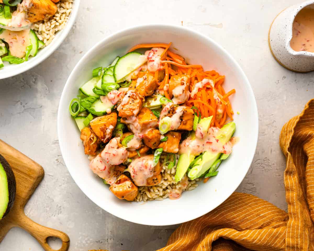 Overhead shot of finished salmon bowl topped with fresh veggies and drizzled with Bang Bang sauce.