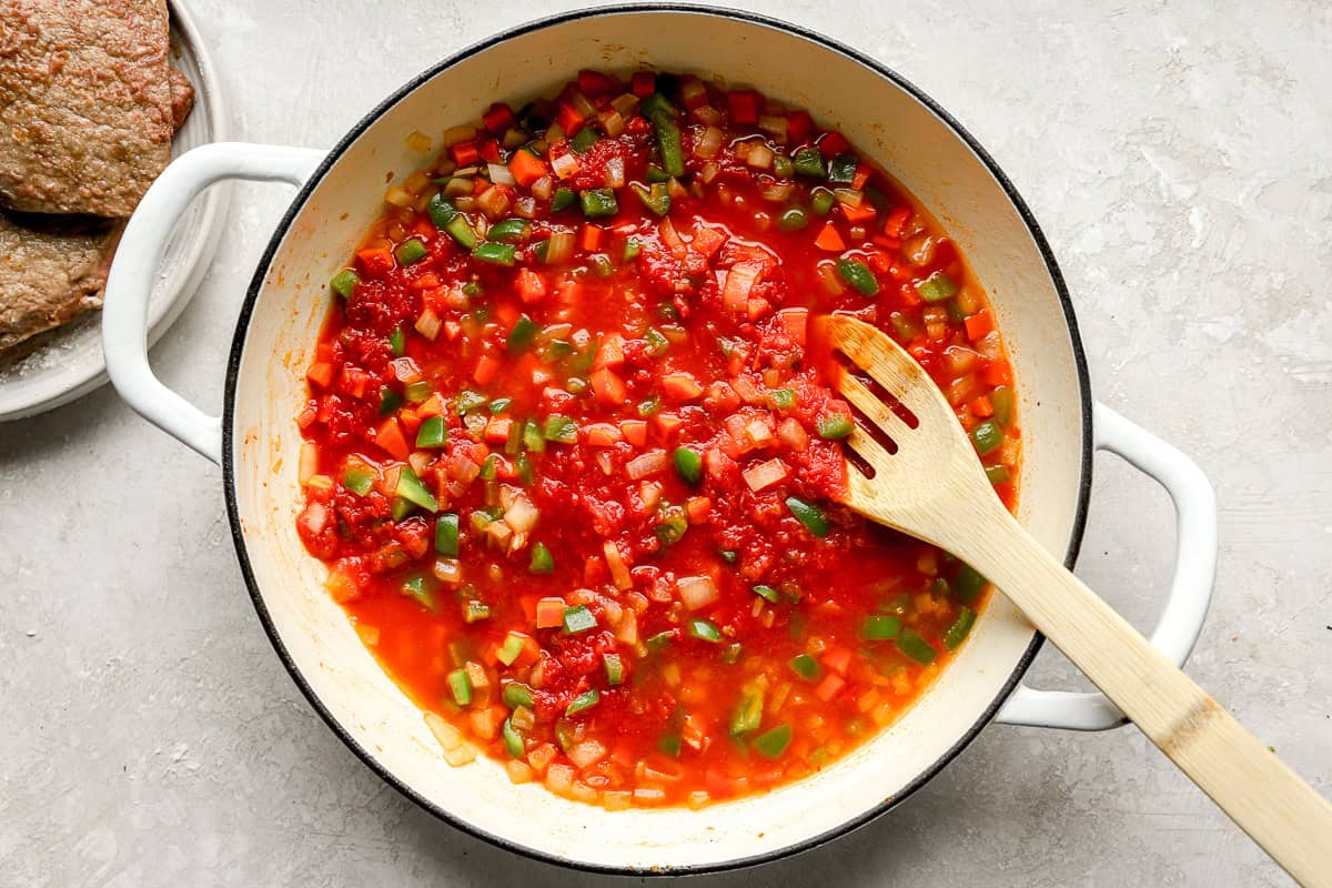 Skillet filled with sautéed carrots, onions, and green bell peppers in a tomato sauce mixture.