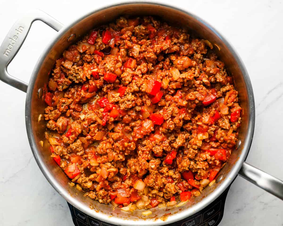 Sausage and veggie mixture in the skillet after adding tomato paste and seasoning, beginning to thicken.
