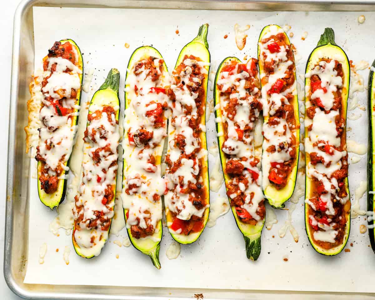 Stuffed zucchini boats on a baking sheet topped with melted mozzarella cheese right out of the oven.