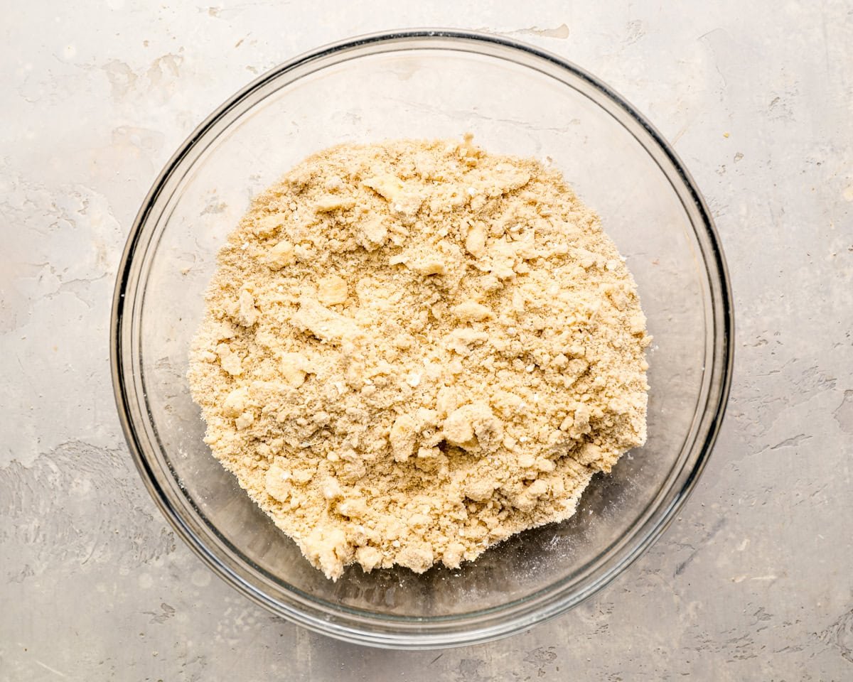 Glass bowl with crumbly crisp topping mixture made with butter, flour, sugar, and oats.