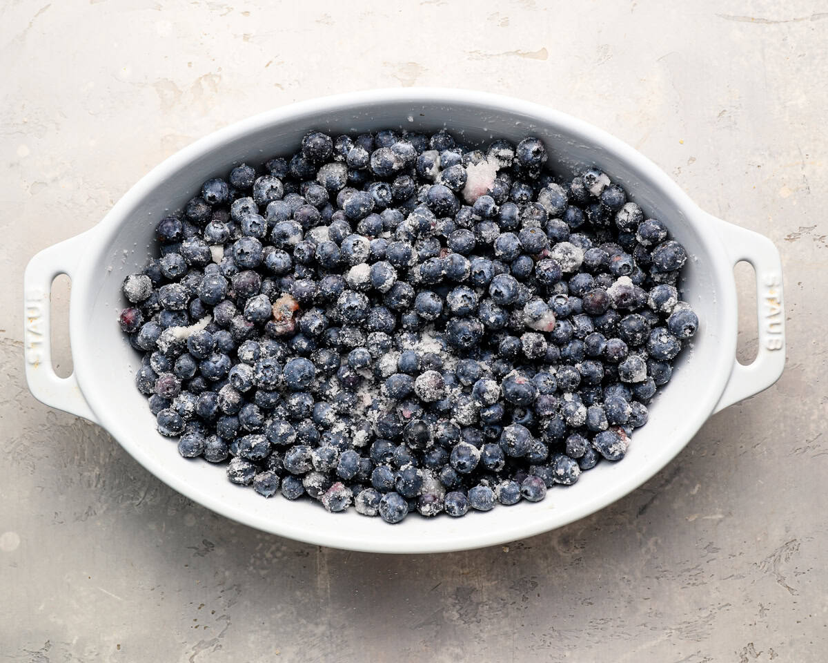 Baking dish filled with sugared blueberries evenly spread across the bottom.