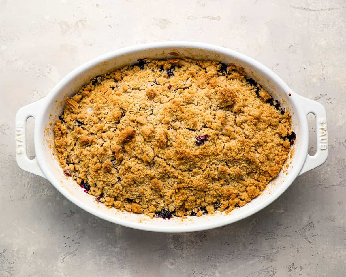 Freshly baked blueberry crisp in a white baking dish with a golden-brown topping.