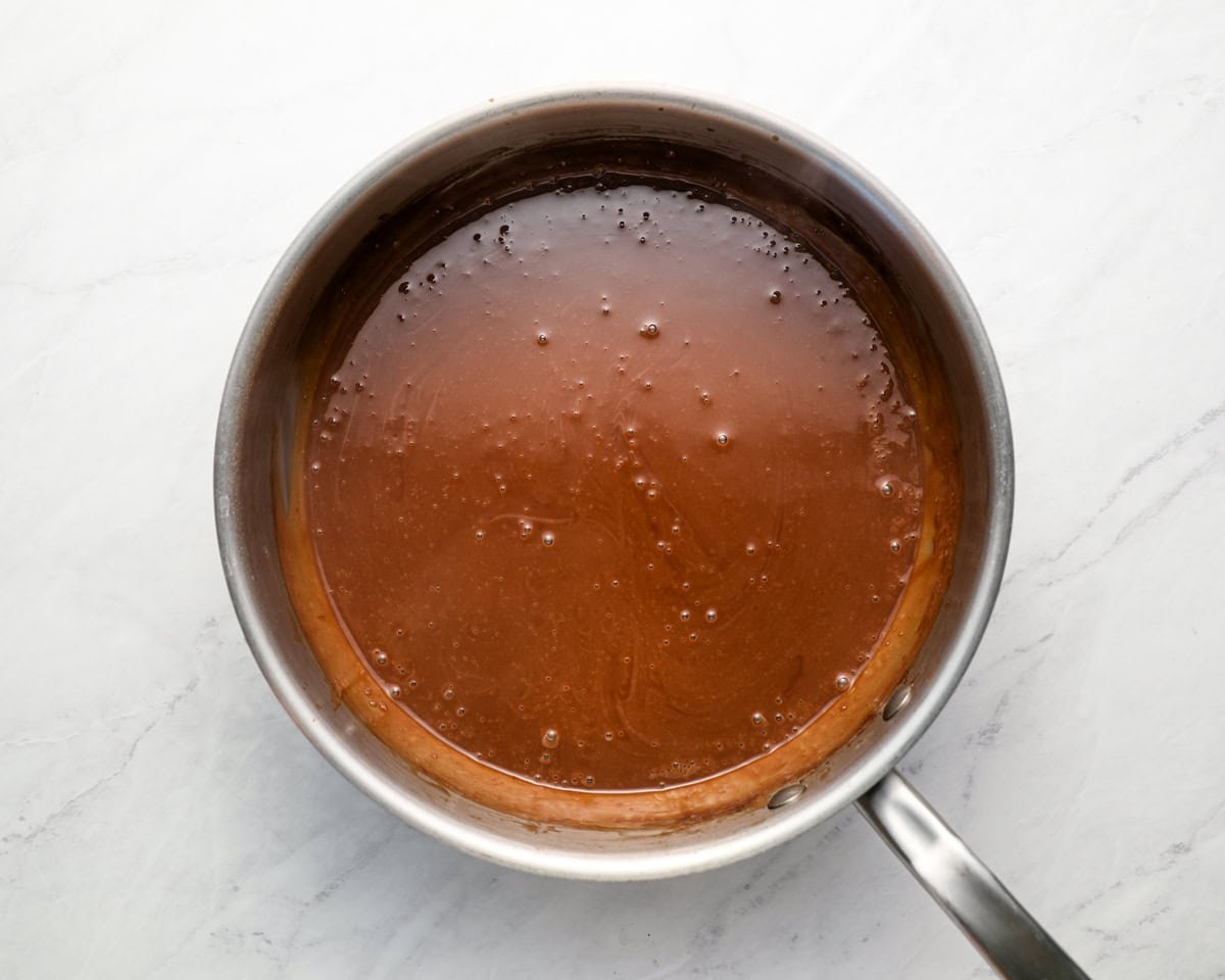 Fully thickened chocolate pudding in a saucepan with a smooth, glossy surface, just removed from heat.