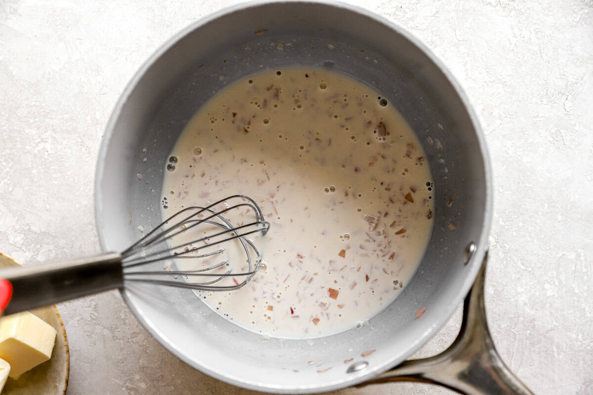 Heavy cream whisked into the shallot mixture in a saucepan for beurre blanc.