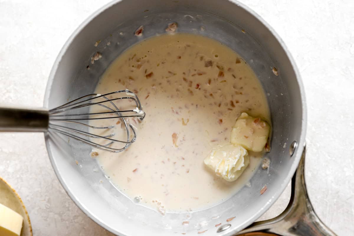 Cubes of butter melting into the cream and shallot mixture while making beurre blanc